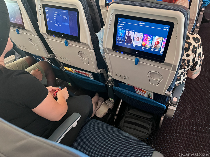 a person sitting in an airplane with a television screen