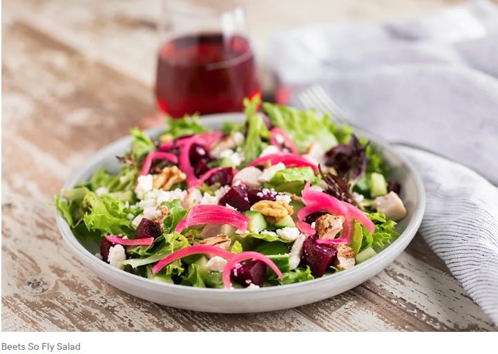 a plate of salad with a fork and a glass of wine