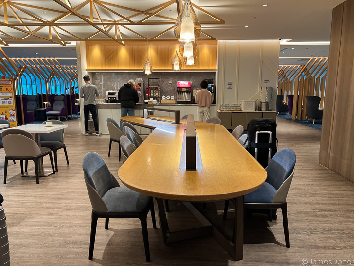 a large table with chairs in a room with people standing around