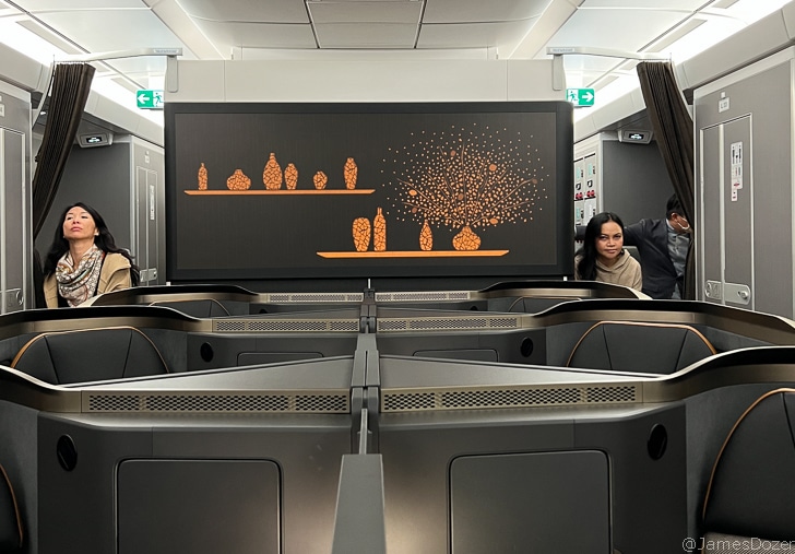 a group of people sitting in a room with a large screen