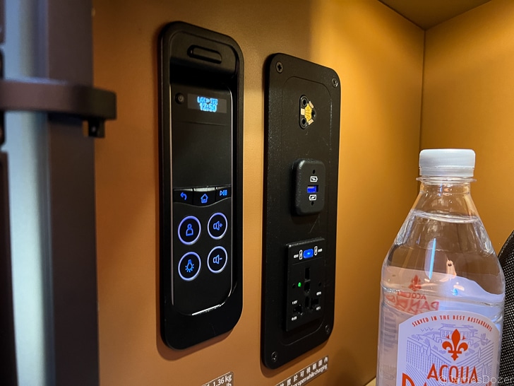 a bottle of water next to a wall with switches