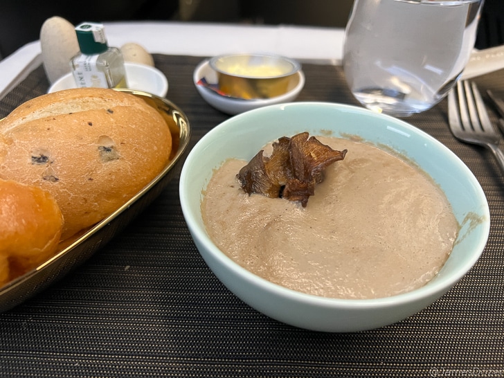 a bowl of food next to a loaf of bread