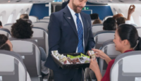 a man in a suit holding a basket of food in a plane