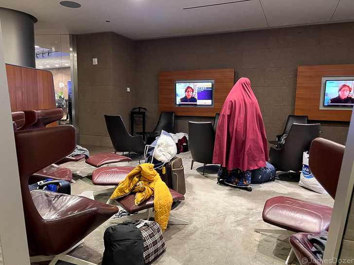 a person in a red robe in a room with chairs and a television