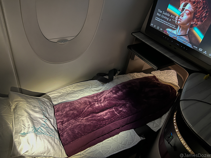 a bed with a blanket and a television in the back of it