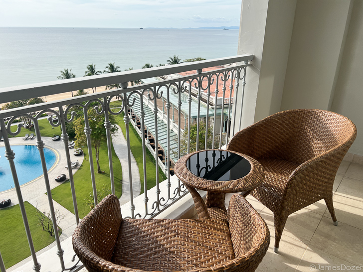 a chair and table on a balcony overlooking a body of water