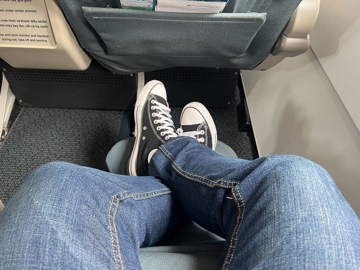 a person's legs in a seat with a pair of black shoes