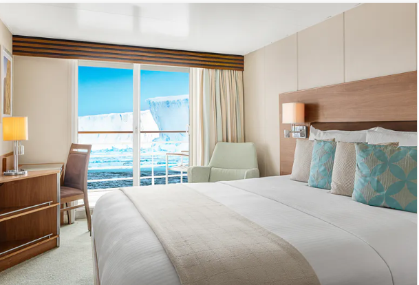 a room with a bed and chairs and a large window