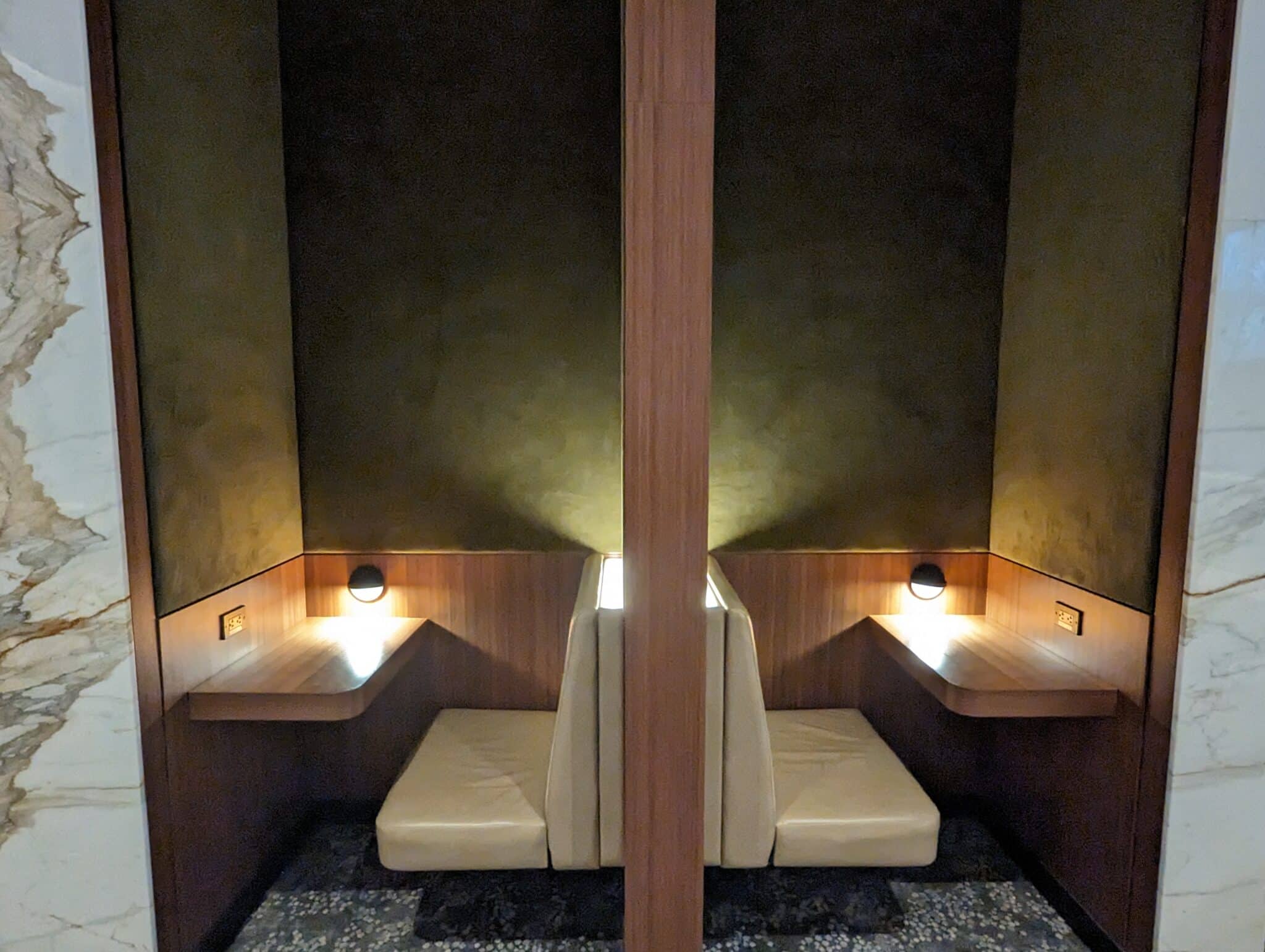 a two white seats in a room with a wall and lights