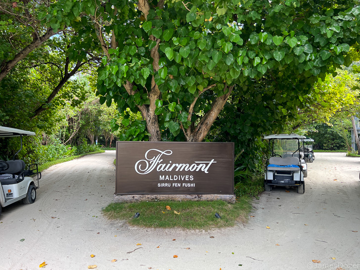 a sign with a golf cart parked next to a tree