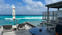 a deck with chairs and a pool by the ocean