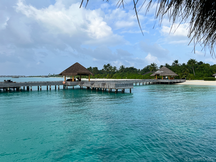 a dock over water with trees and a beach