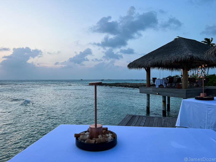 a table with a tray of food on it by a dock with a hut and water