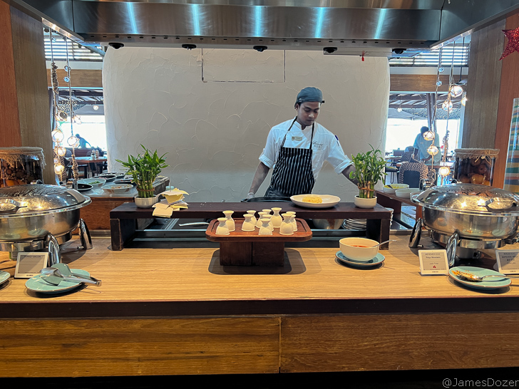 a man standing behind a counter with food on it