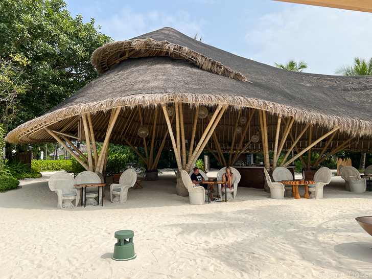 a hut with a straw roof and people sitting at a table