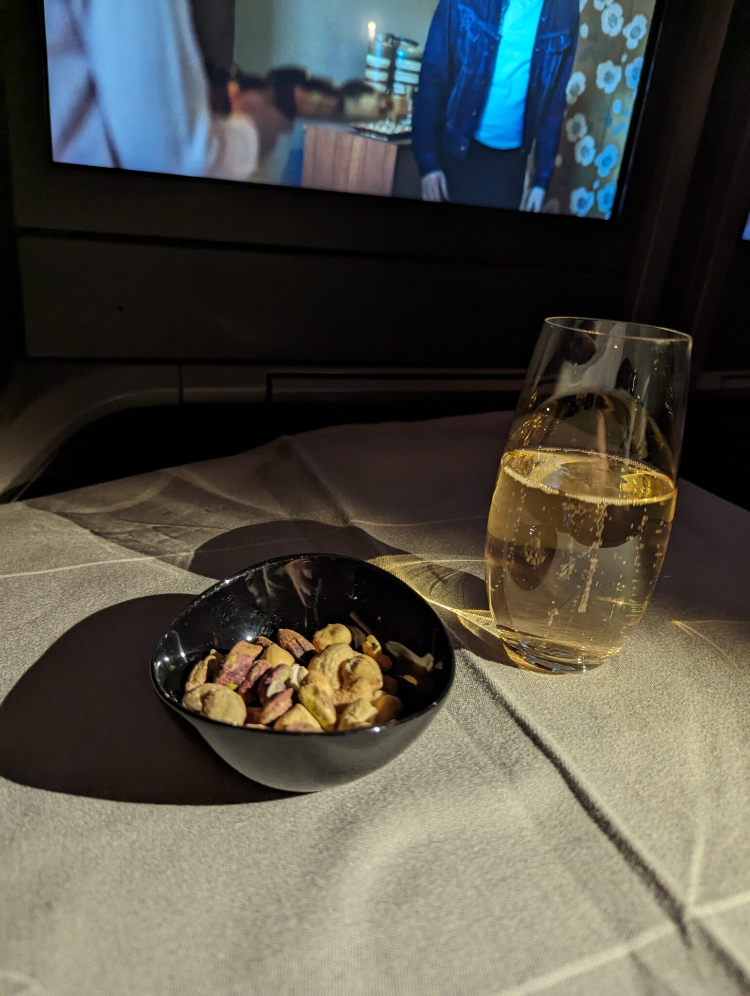a bowl of nuts and a glass of champagne next to a television