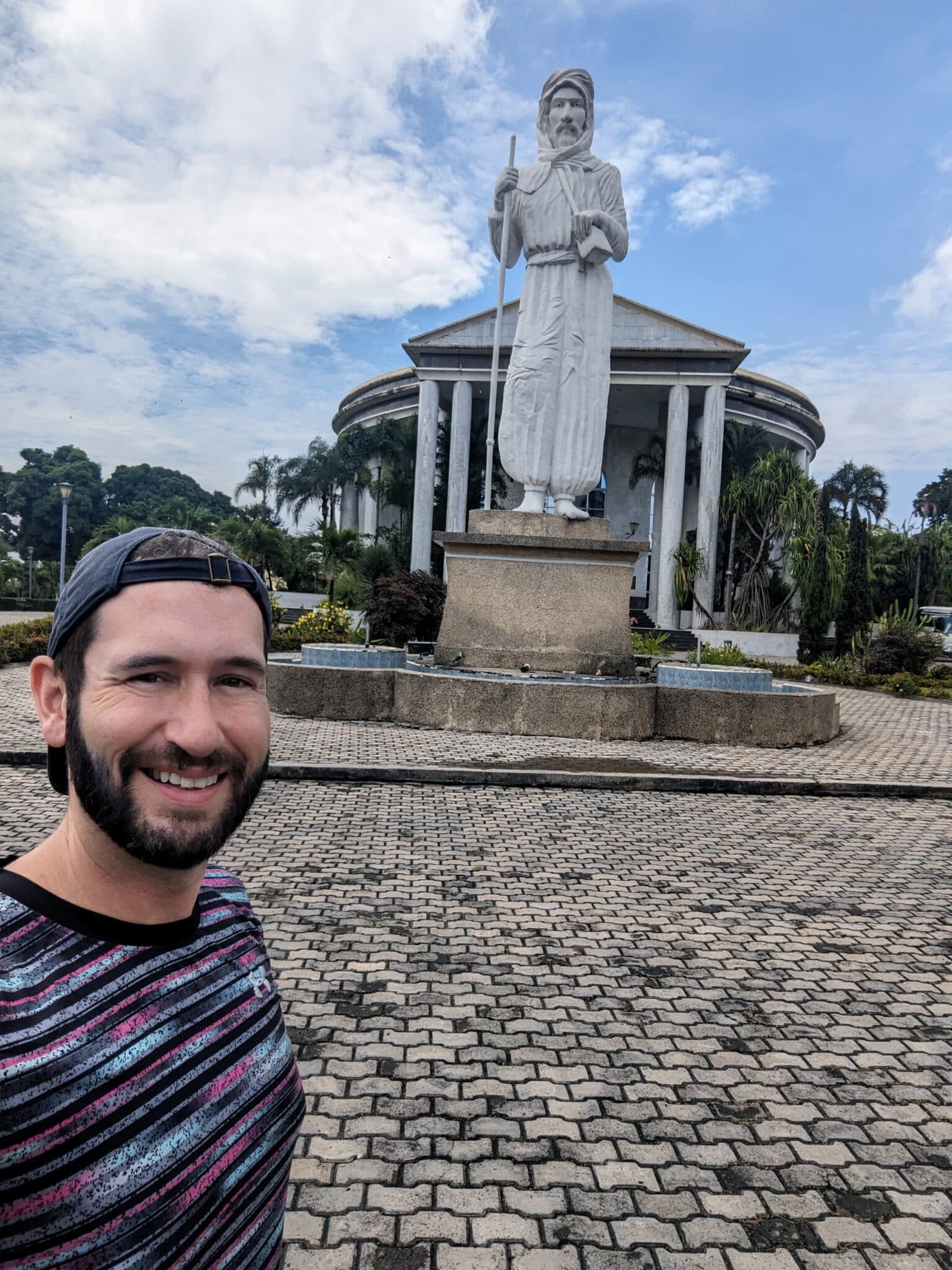 a man taking a selfie in front of a statue
