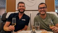 two men sitting in chairs holding drinks and smiling
