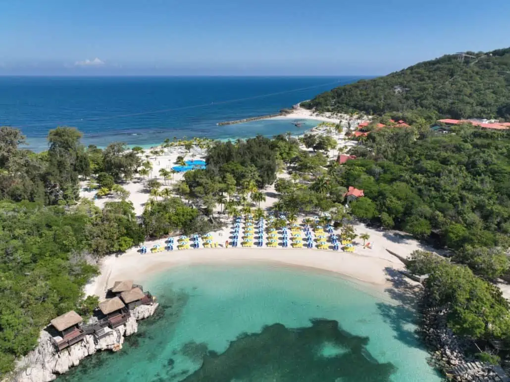 a beach with umbrellas and chairs and trees around it