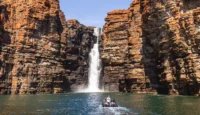 a group of people in a boat in the water surrounded by rocks