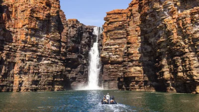 a group of people in a boat in the water surrounded by rocks