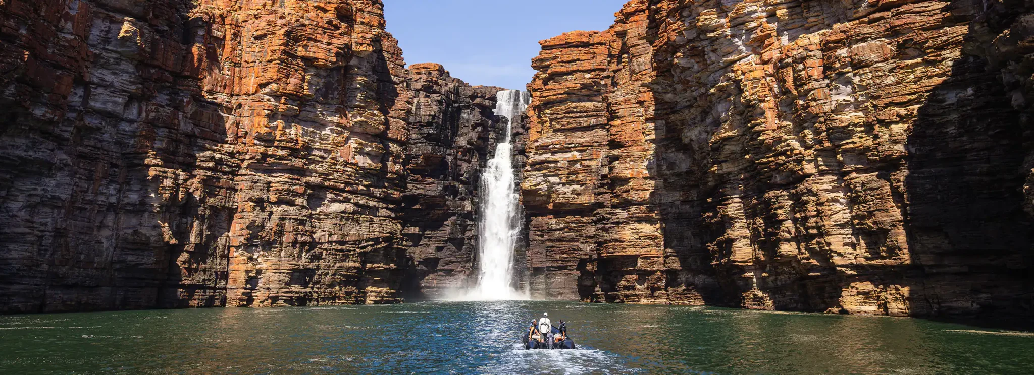 a group of people in a boat in the water surrounded by rocks