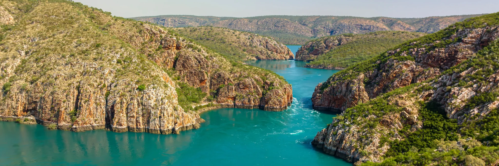 a blue water with rocks and trees