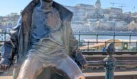 a statue of a boy sitting on a rail