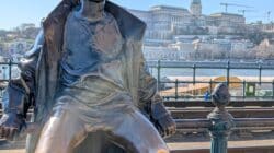 a statue of a boy sitting on a rail