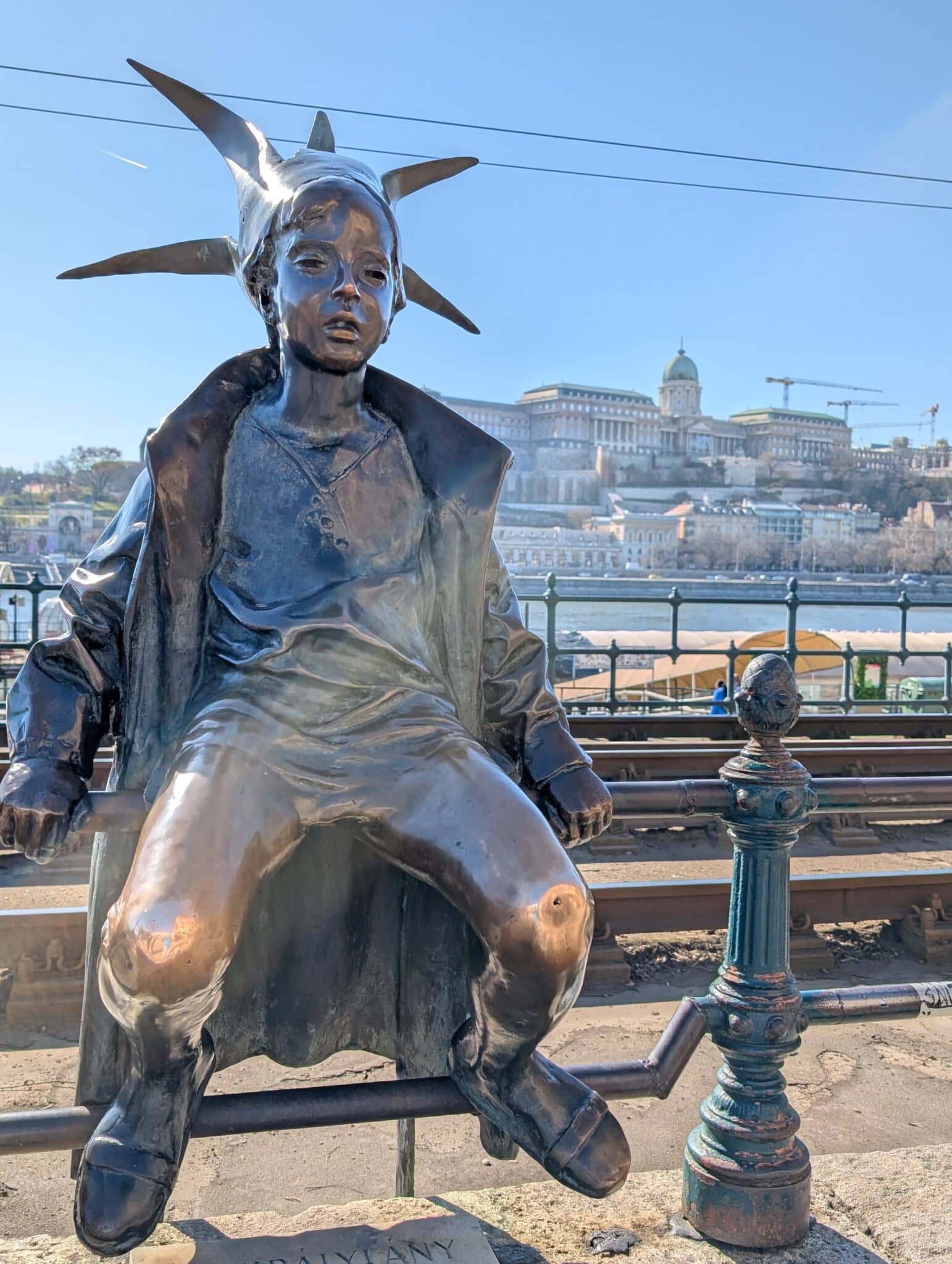 a statue of a boy sitting on a rail