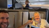 a man and woman sitting in an airplane with glasses of champagne