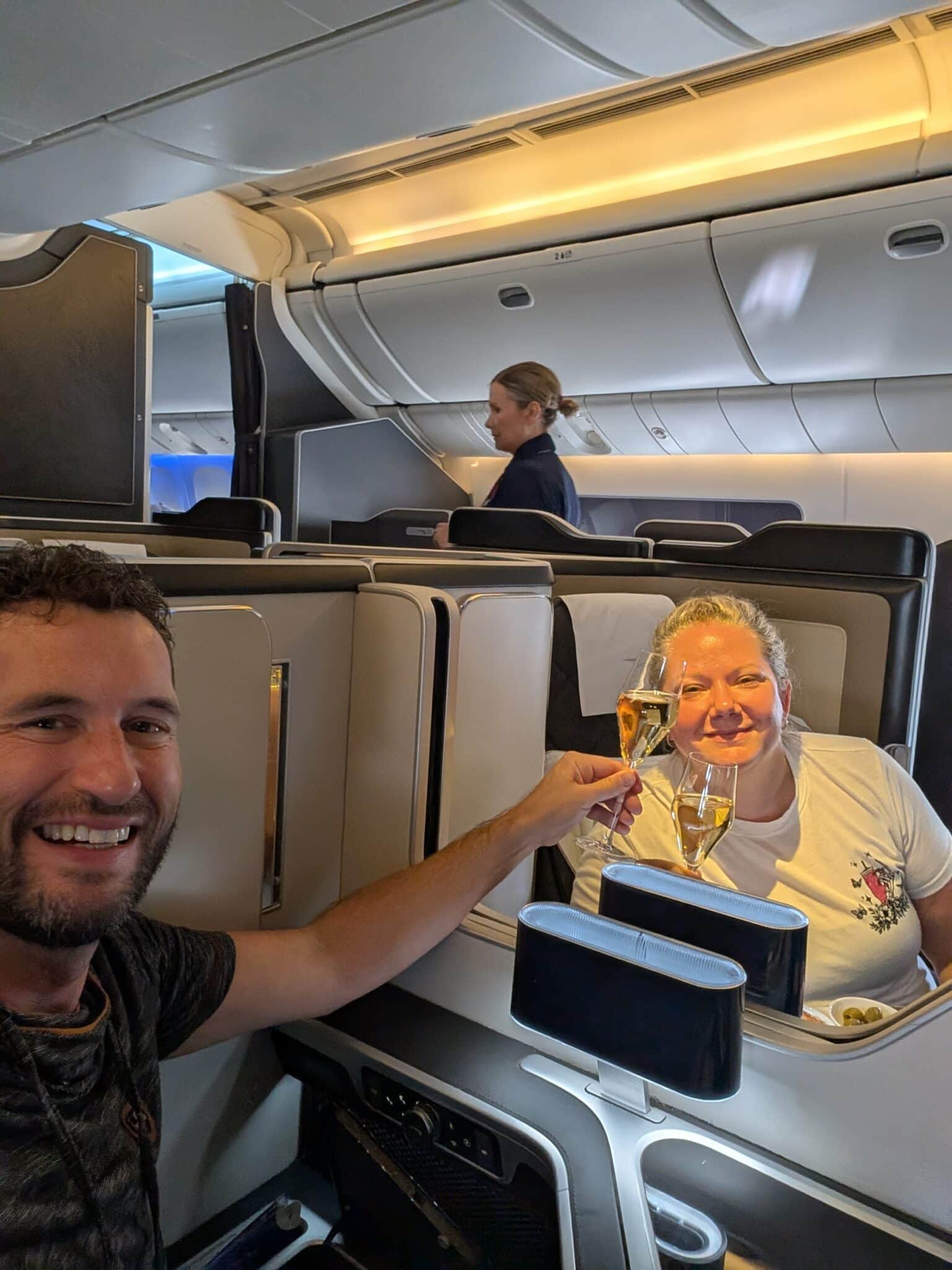 a man and woman sitting in an airplane with glasses of champagne