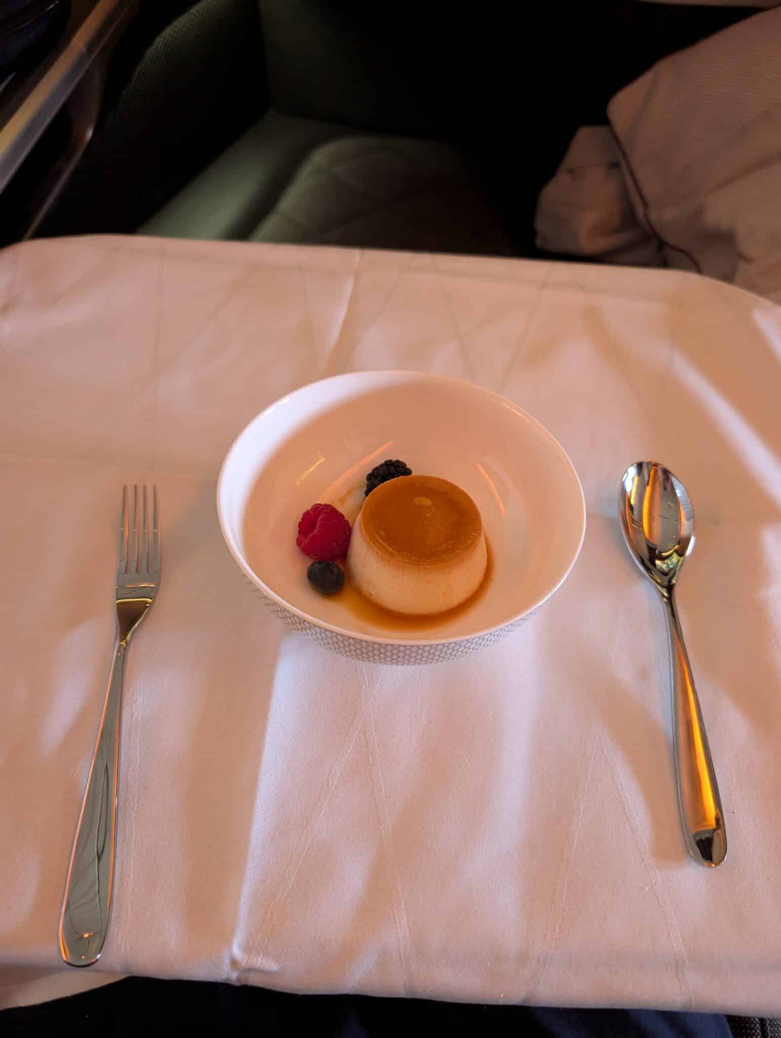 a plate of dessert with berries and a spoon on a table