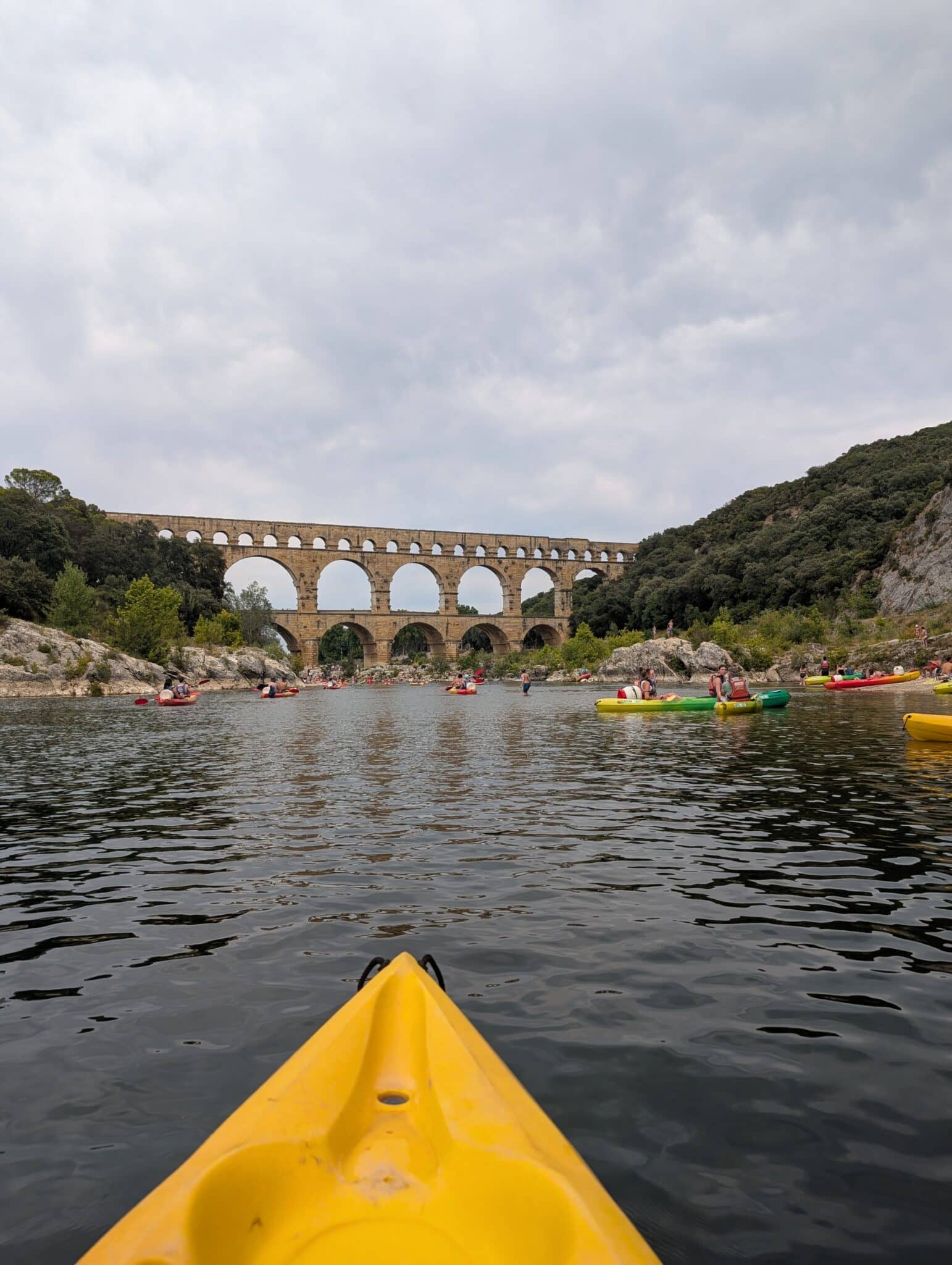 a group of people in kayaks on a river with a bridge in the background