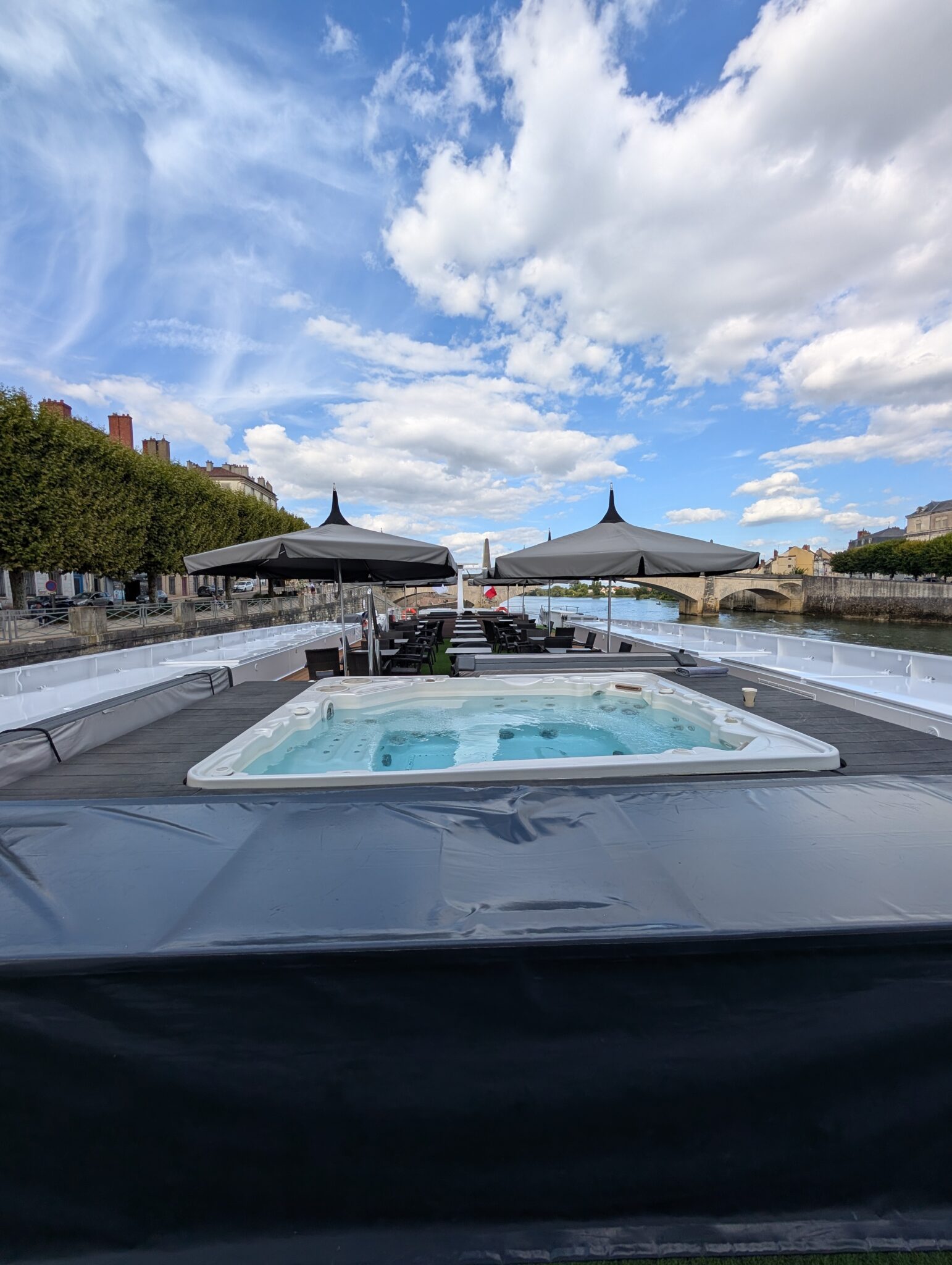 a hot tub on a dock with umbrellas