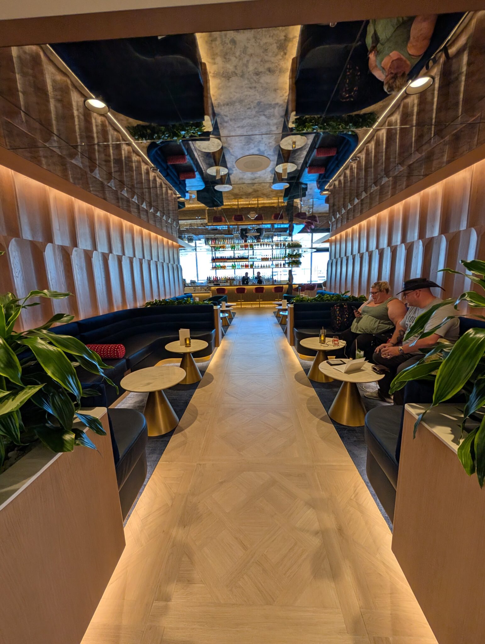 people sitting in a room with tables and plants