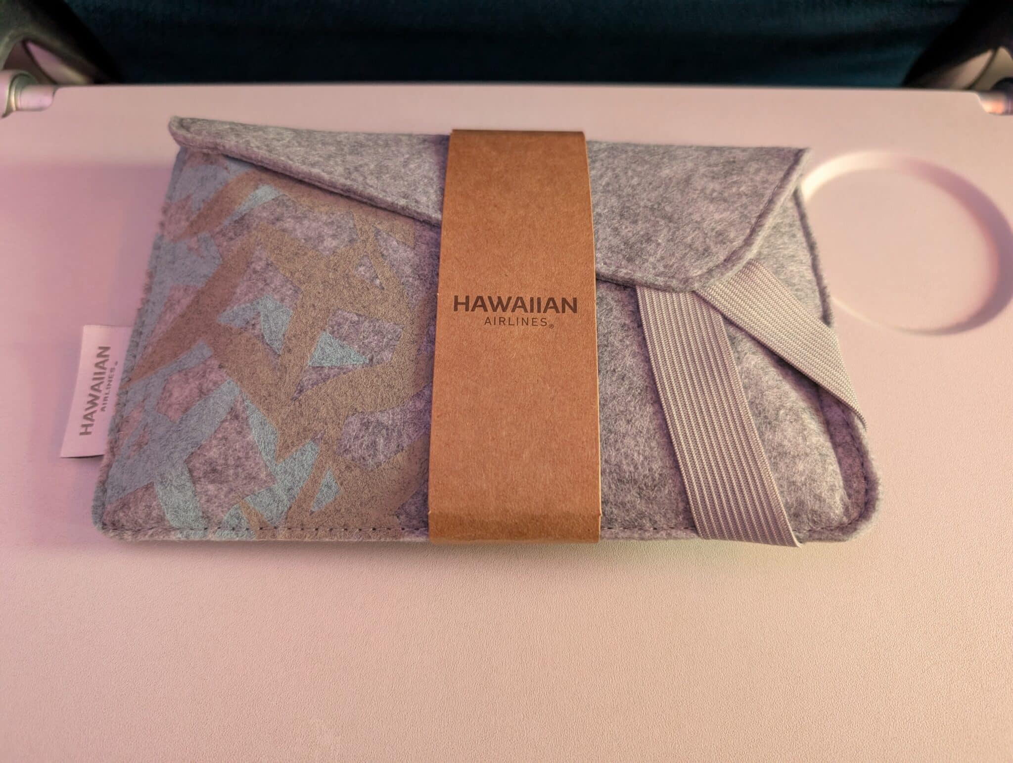 a grey and blue pouch with a brown tag