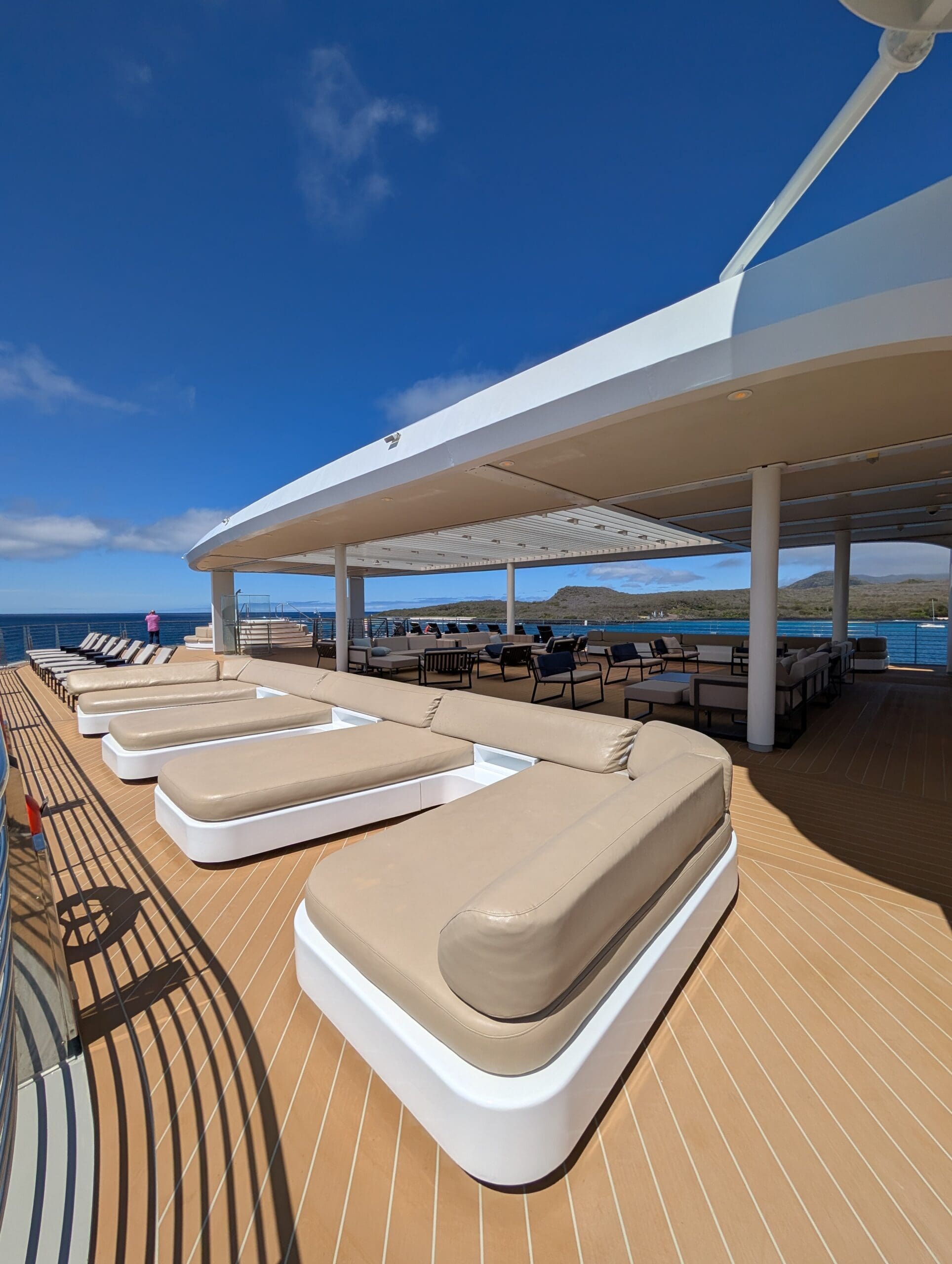 a deck of a boat with lounge chairs on the water