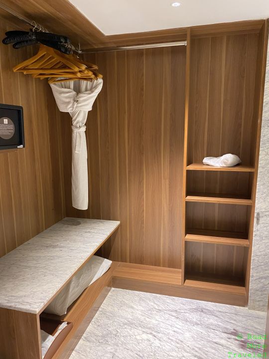 a wooden closet with a bench and a white robe
