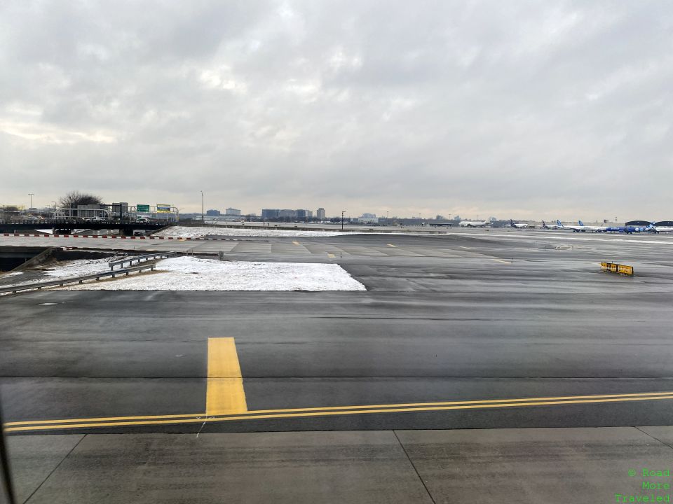 an empty runway with snow and buildings in the background
