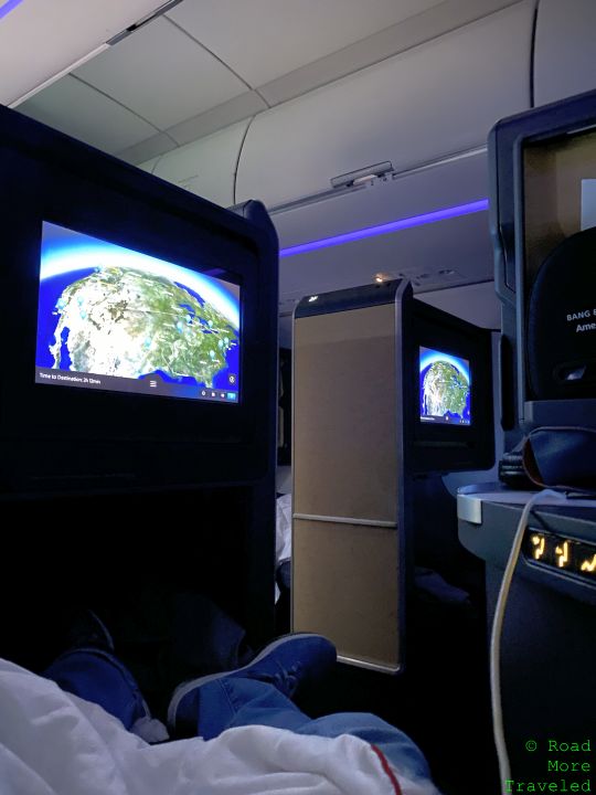 a person sitting in an airplane with a television screen
