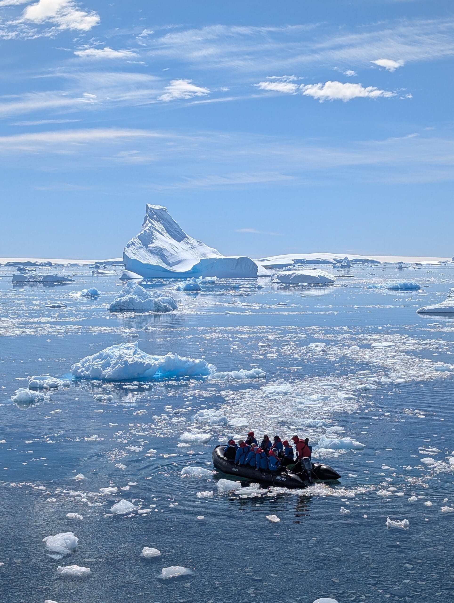 a group of people in a boat in the water with icebergs in the background